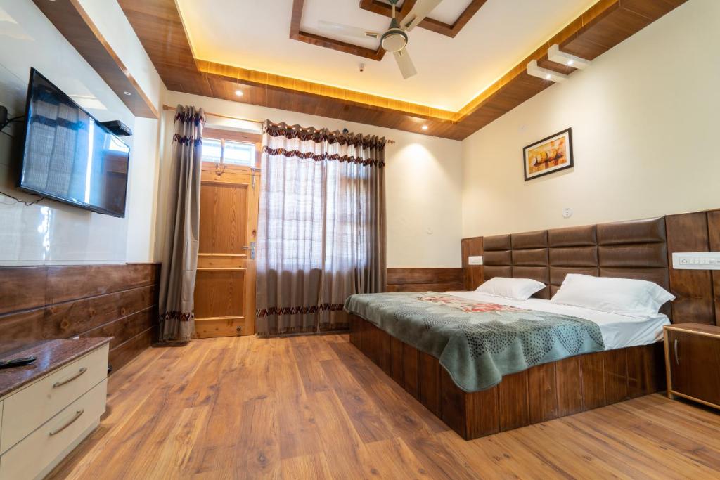 a bedroom with a bed and a tv on a wall at Mathan View Homestay in Shamshi