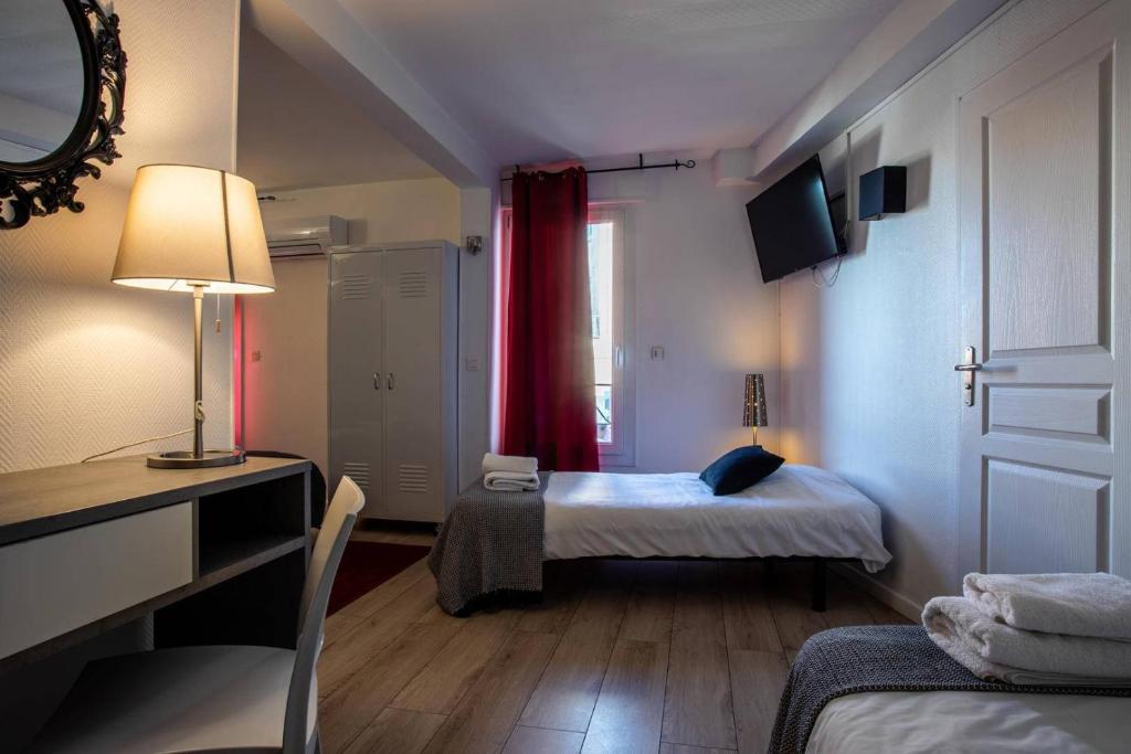 a room with two beds and a desk and a mirror at Hôtel Le Mistral in Marseille