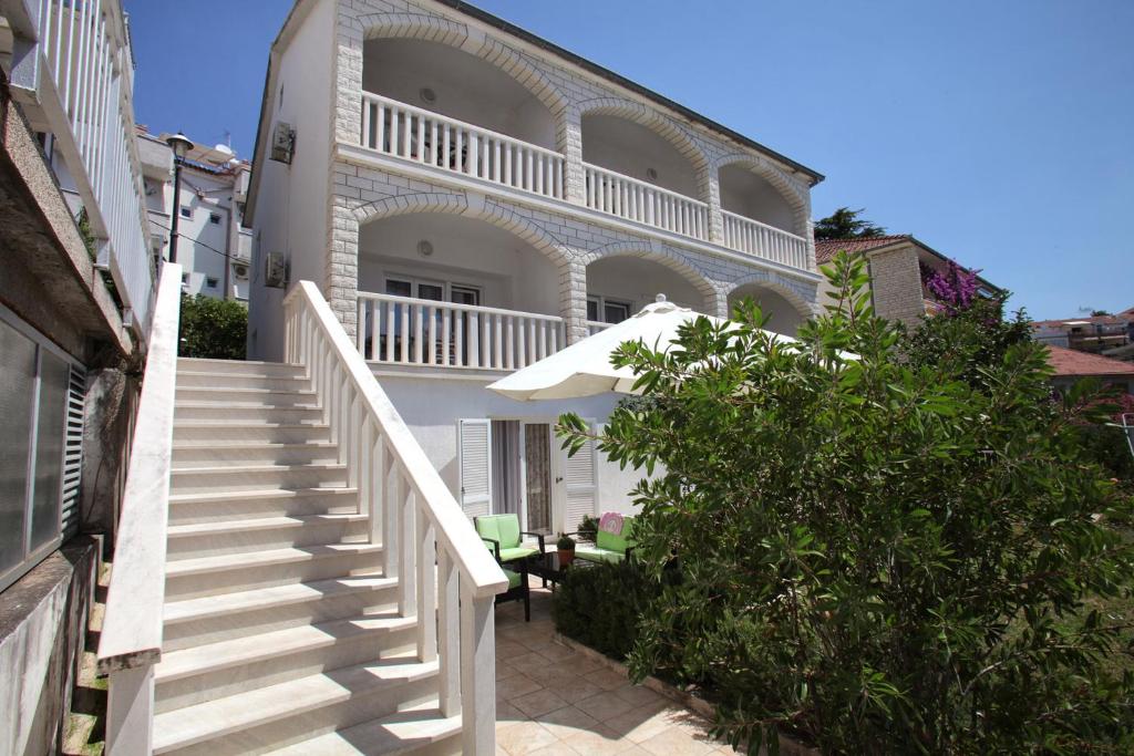 ein weißes Haus mit Treppe und Schirm in der Unterkunft Apartments MJM in Trogir