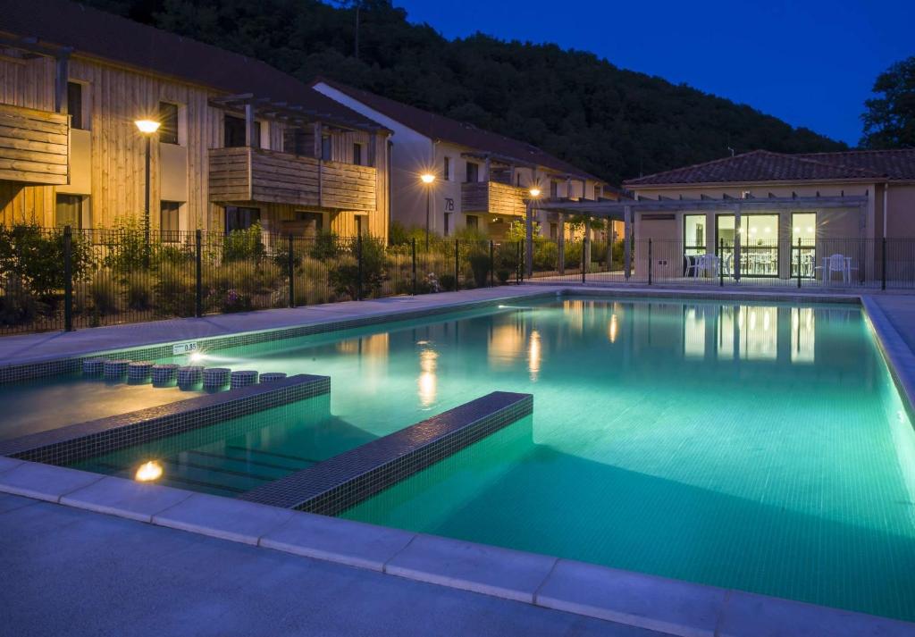 una piscina en una casa por la noche en Vacancéole - Résidence Le Clos du Rocher en Les Eyzies-de-Tayac