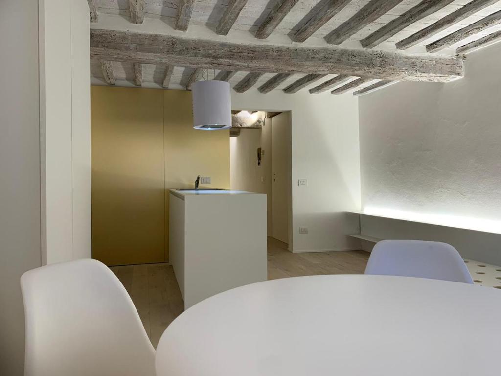een kamer met witte stoelen, een tafel en een plafond bij Pispini Apartment in Siena