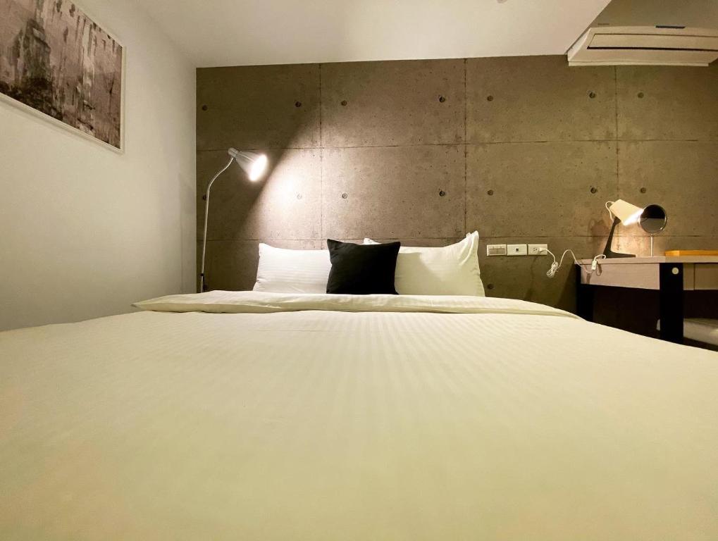 a bedroom with a large white bed and a lamp at M Taipei Hotel in Taipei