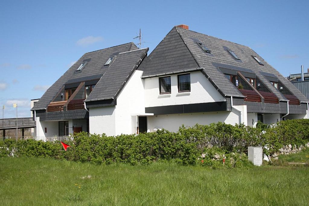 una gran casa blanca con techo gris en Wohnung Tide, en Hörnum
