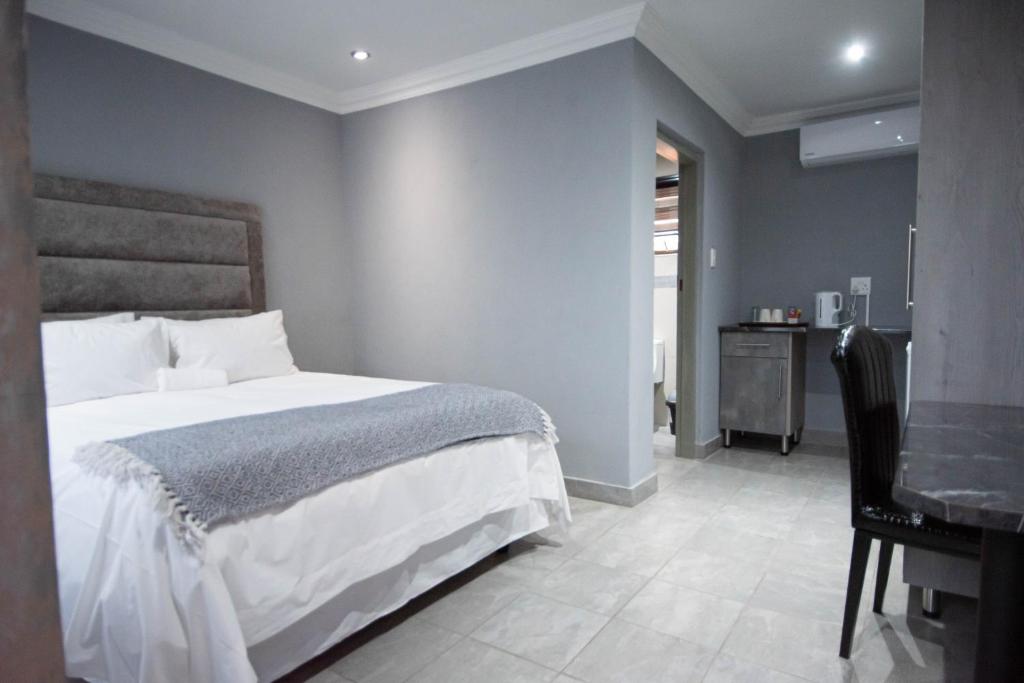 a bedroom with a bed and a desk and a desk at President Guest Lodge in Louis Trichardt