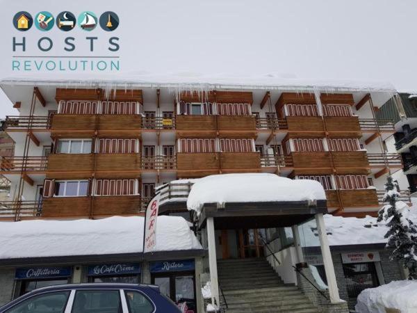 a snow covered building with a car parked in front of it at Ski slopes apartment in Sestriere