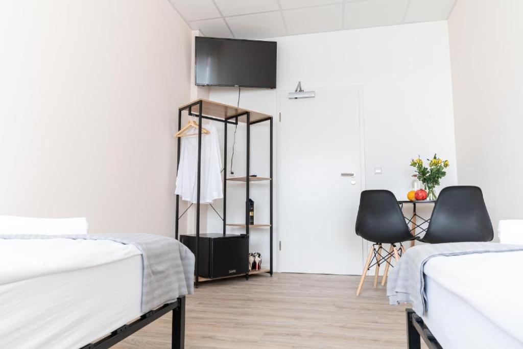 a bedroom with two beds and a table and chairs at Hostel Messe Laatzen in Hannover