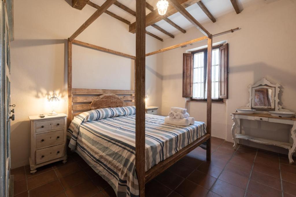 a bedroom with a canopy bed and a dresser at agriturismo l'arte dei semplici in Montalcino