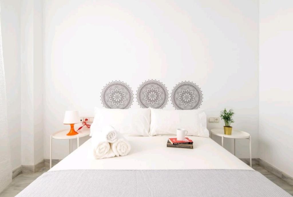 een witte slaapkamer met een wit bed en 2 tafels bij Casa de la Alameda in Sevilla