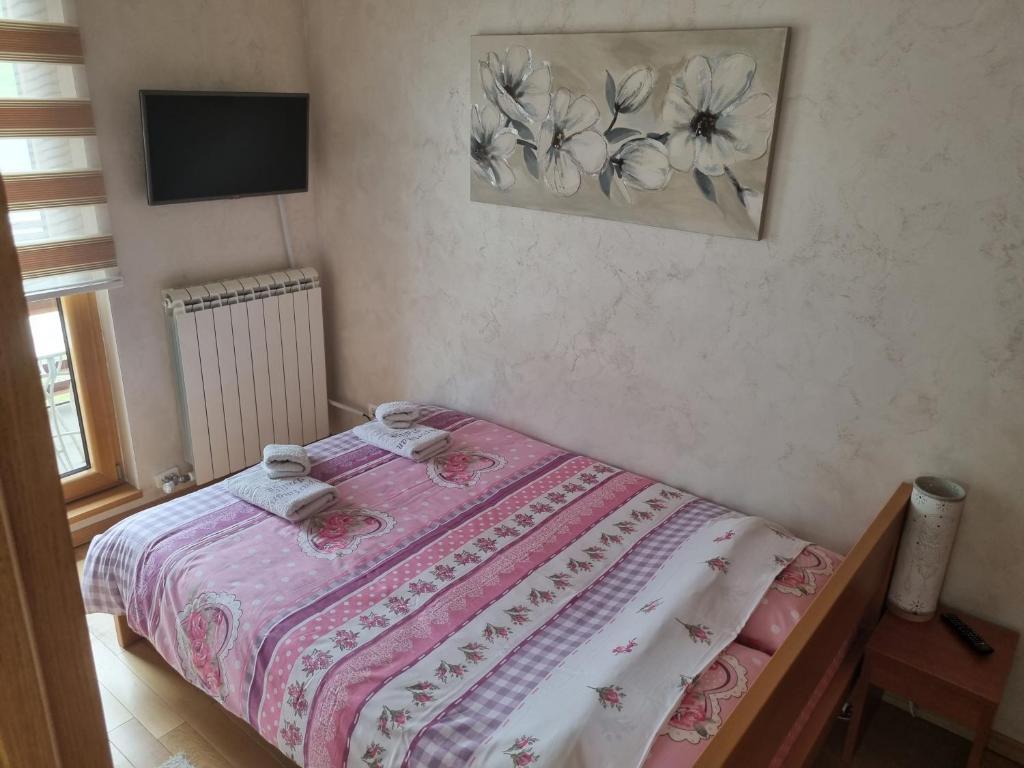 a small bedroom with a bed with a pink blanket at Apartman Dalija in Zlatibor