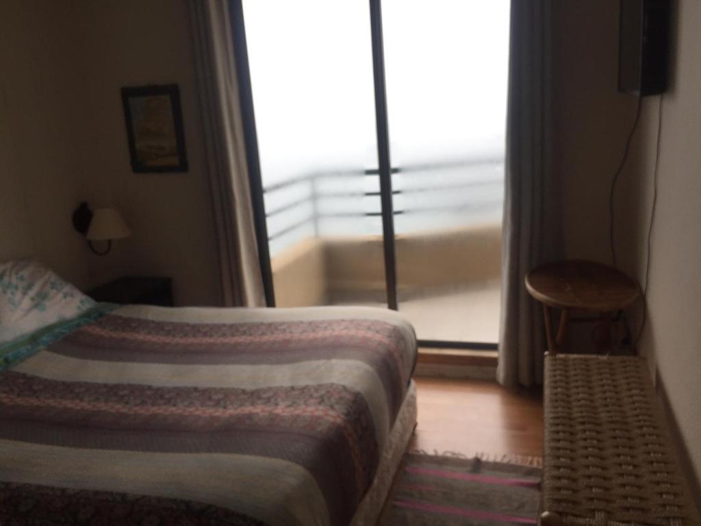 a bedroom with a bed and a window with a balcony at Horcon Condominio CAUCAU in Horcón