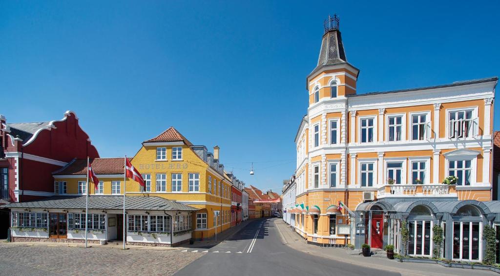 une rangée de bâtiments avec une tour d'horloge dans une rue dans l'établissement Hotel Ærø, à Svendborg