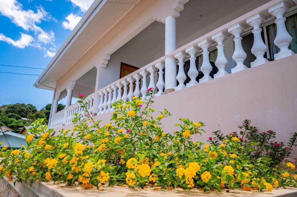 een wit huis met bloemen op een balkon bij Athara's Apartment in Anse Possession
