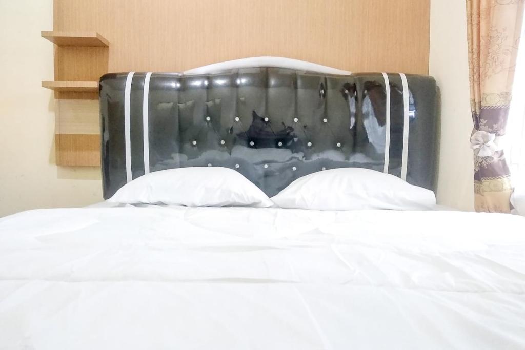 a bed with a black headboard and two pillows at Griya De Riz Syariah Mitra RedDoorz in Jambi
