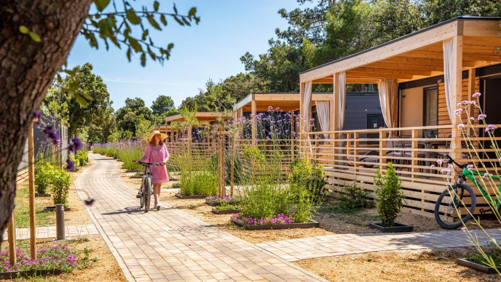 Eine Frau, die ihr Fahrrad in einem Garten läuft in der Unterkunft Mobile Homes Lopari in Nerezine