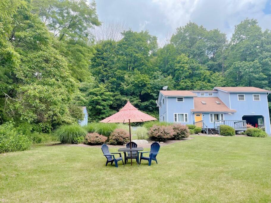 a table with chairs and an umbrella in a yard at Le Chalet Blue near Camelback Poconos, 6 Beds, Sleeps 10, Pool in Stroudsburg