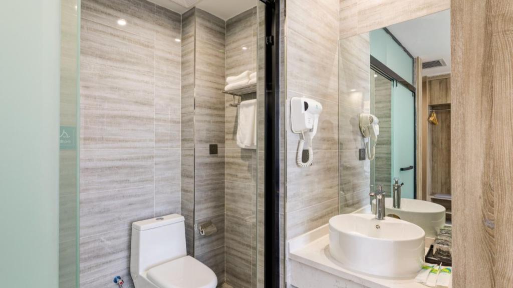 een badkamer met een toilet, een wastafel en een spiegel bij Suoxing Hotel Longxian Passenger Bus Station in Long