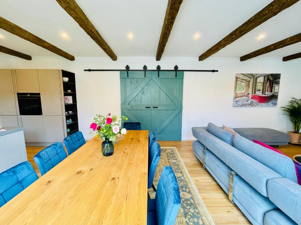 a living room with a wooden table and blue couches at Cottage Wilkenburg - das luxuriöse und idyllische Ferienhaus in Hemmingen