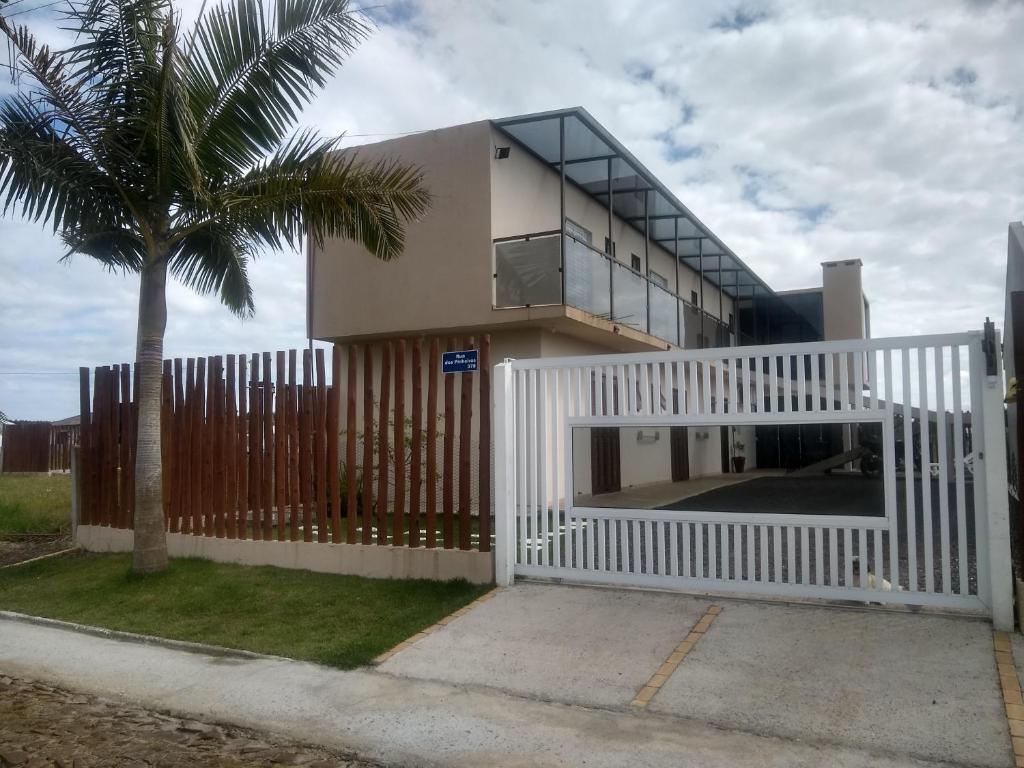 een huis met een wit hek en een palmboom bij Hostel Pousada Casa da Praia in Passo de Torres