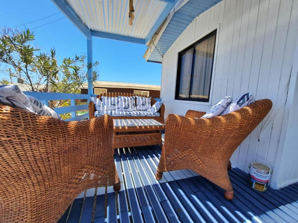 two wicker chairs sitting on a deck on a porch at Casa Bahía Inglesa in Bahia Inglesa