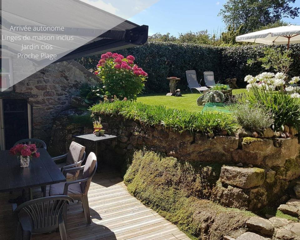einen Garten mit einem Tisch, Stühlen und einem Sonnenschirm in der Unterkunft Cute Normandy Chaleureuse Maison au Cap Levi in Fermanville