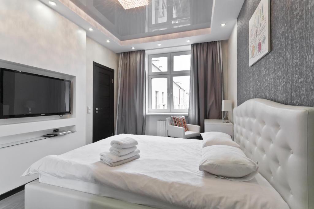 a white bedroom with a bed and a flat screen tv at MinskLux Apartments in Minsk