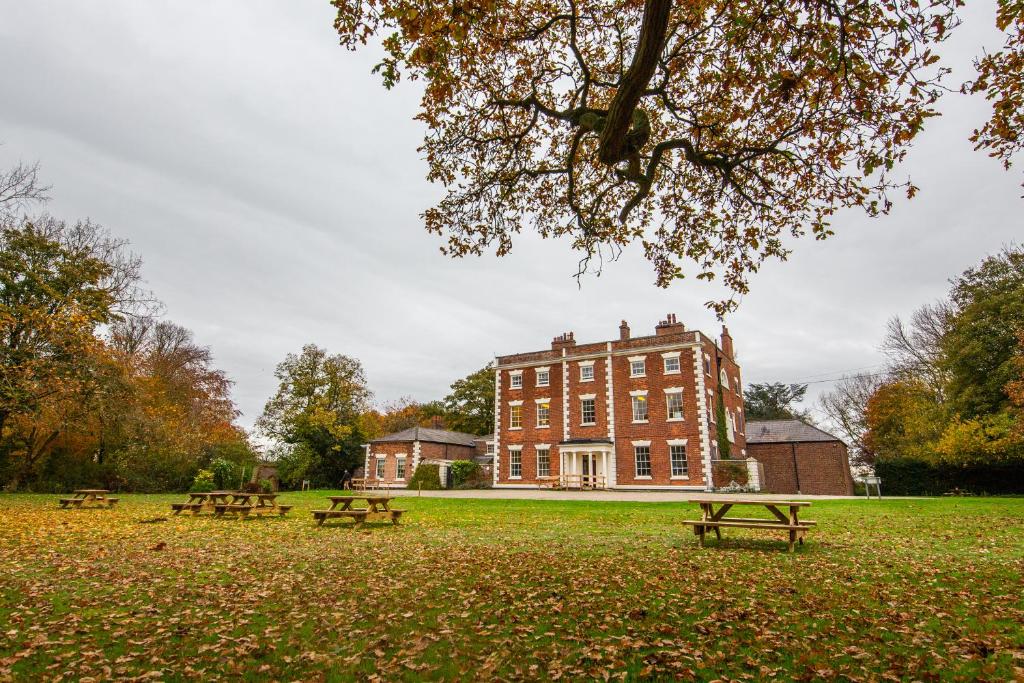 a group of picnic tables in front of a building at YHA Chester Trafford Hall in Dunham on the Hill