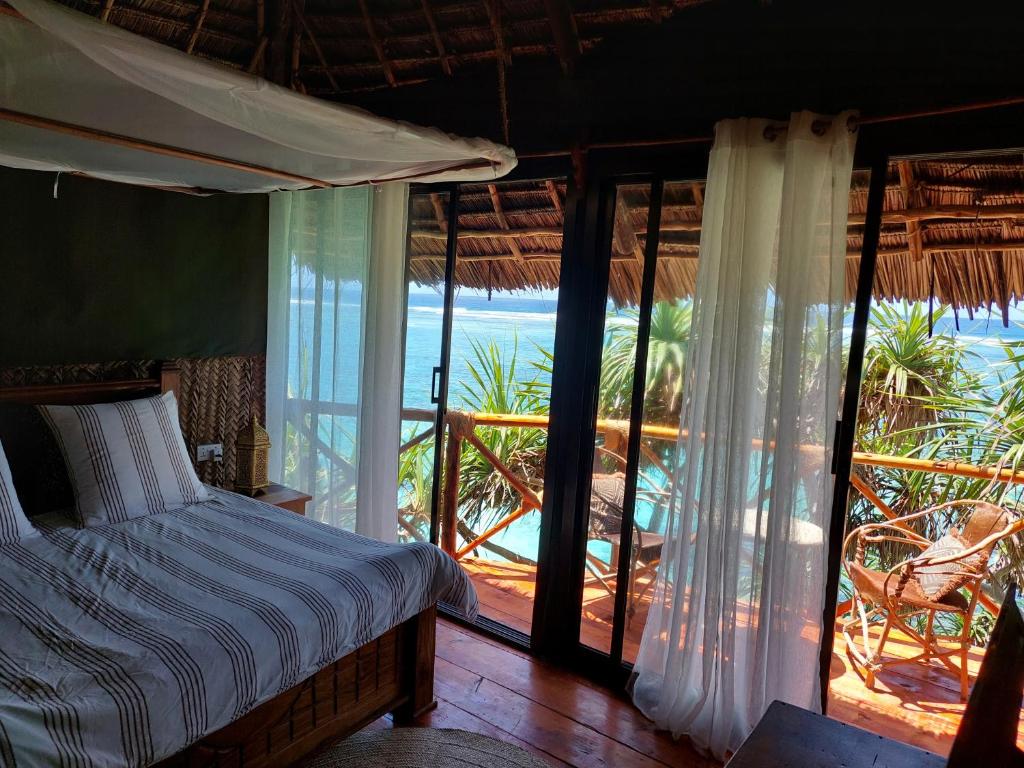 Mtende Beach Bungalow océan view في Mtende: غرفة نوم مع سرير وإطلالة على المحيط