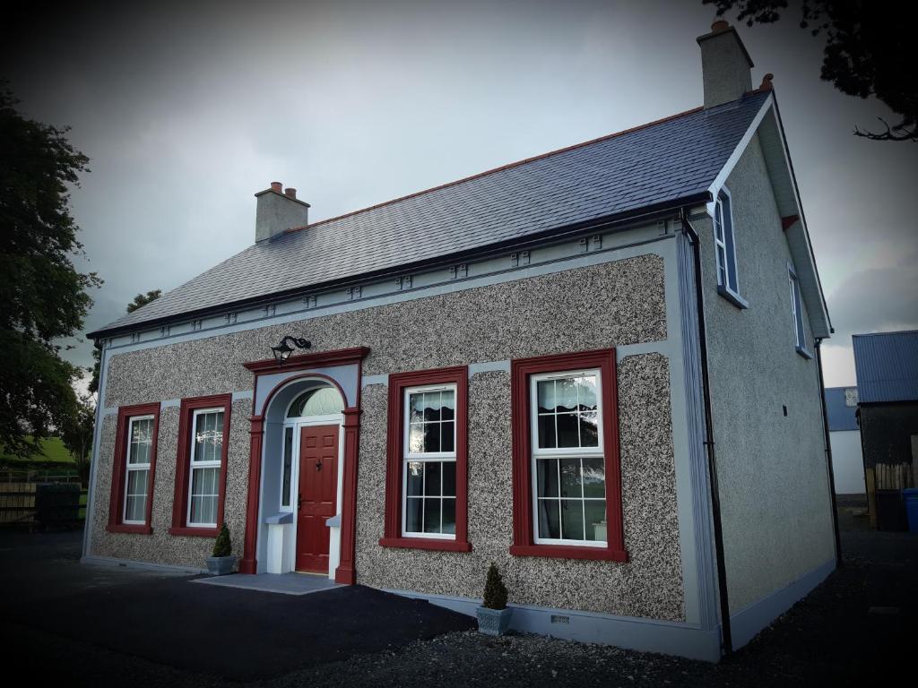 a brick building with red windows and a red door at Rose Cottage in Cullybackey