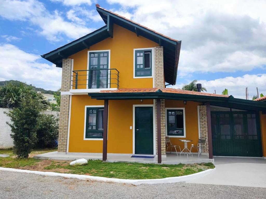 a yellow house with a balcony on a street at Chalé em Condomínio com piscina - Ponta das Canas in Florianópolis