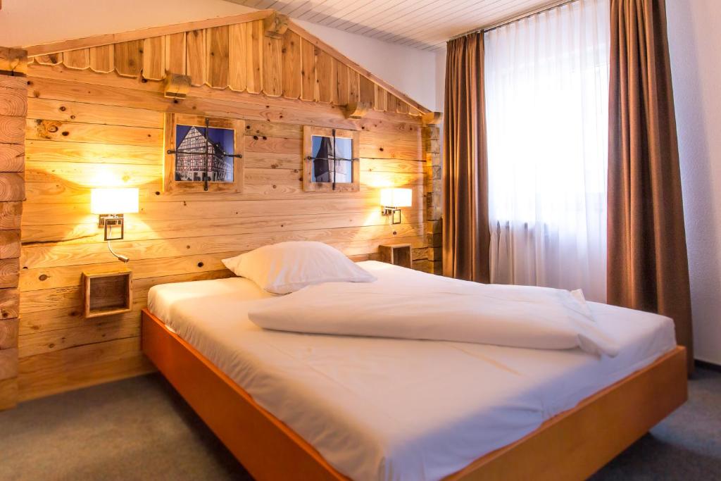 een slaapkamer met een groot bed en een houten muur bij Jäger's Landhaus Rössle in Niedernhall