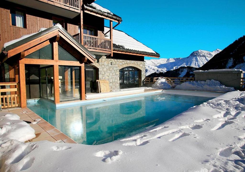 uma casa com piscina na neve em Les Alpages du Corbier A003 em Le Corbier