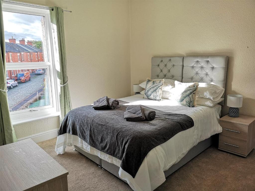 a bedroom with a bed with two towels on it at Douglas House, near Hospital, attractive and comfy 2 bedroom House with enclosed yard to rear in Carlisle