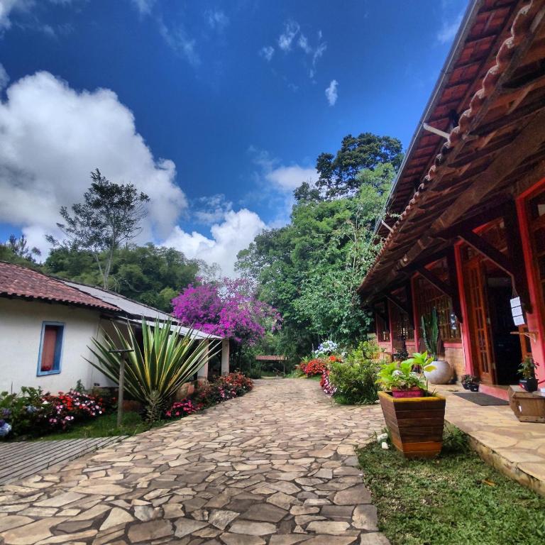 a stone walkway next to a building with flowers at Pousada SerTão de Minas in Conceição da Ibitipoca