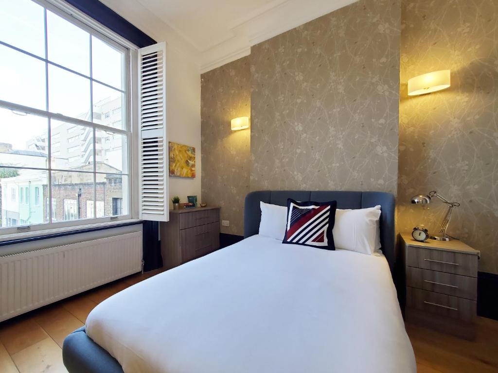 a bedroom with a large bed and a large window at Thames Residences Hyde Park in London