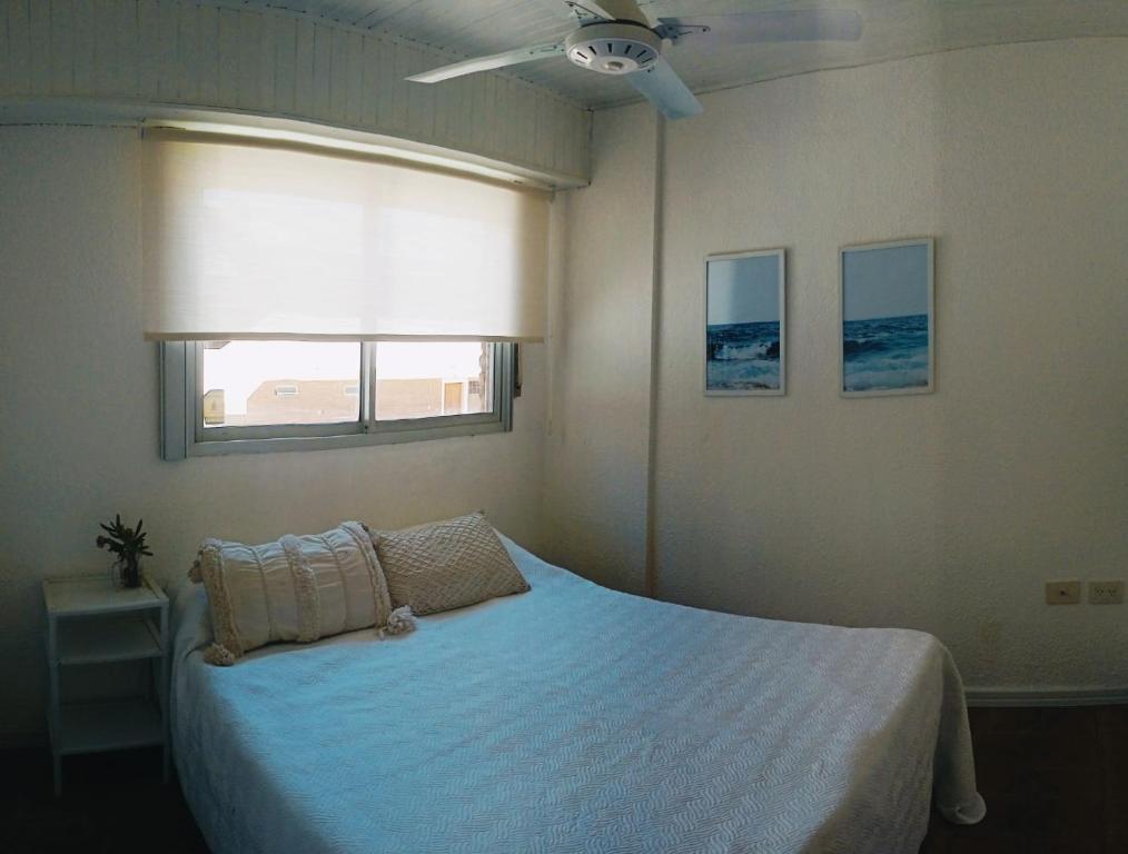 un dormitorio con una cama blanca con ventana a Encantador departament frente al mar 4 Con en Villa Gesell