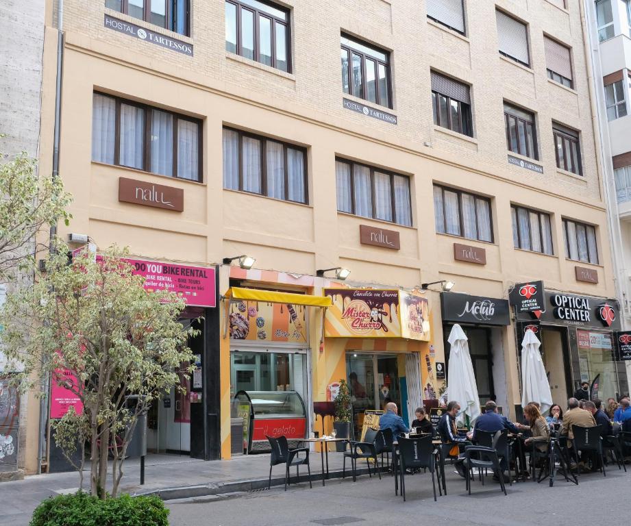 personas sentadas en mesas fuera de un edificio en Hostal Tartessos, en Valencia