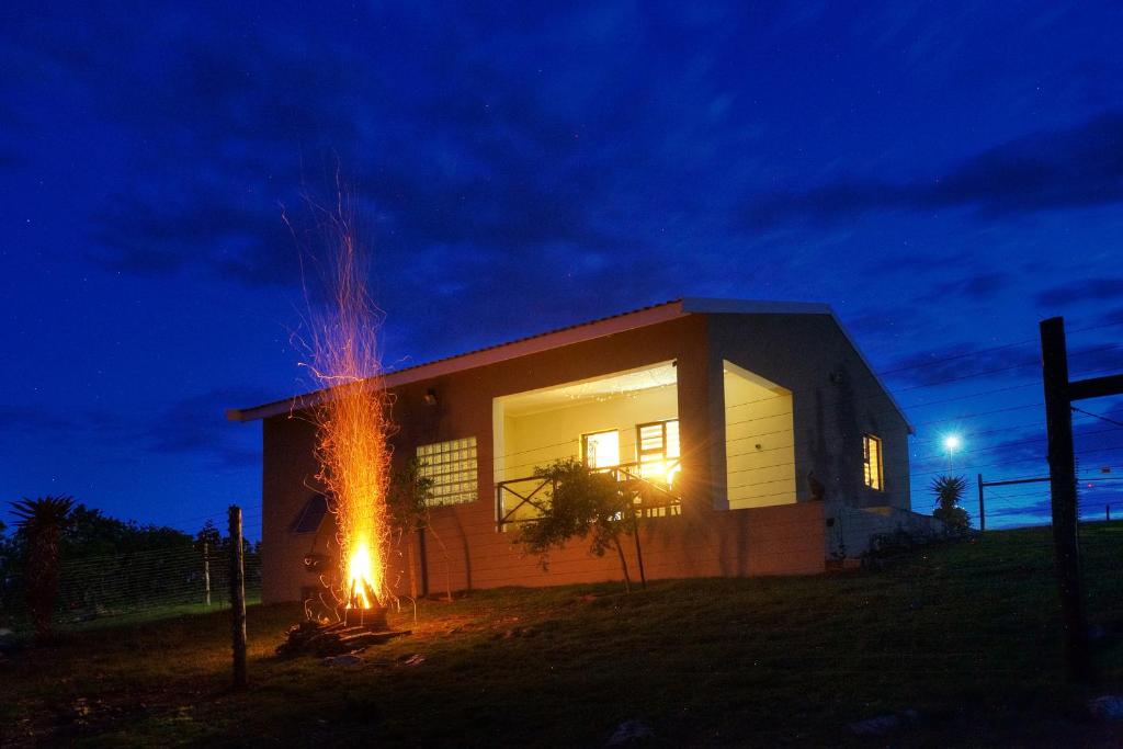 uma casa com um fogo saindo dela à noite em Waggi Mountain Escape em Addo