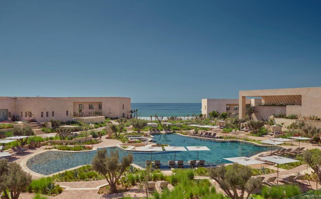 Fairmont Taghazout Bay في تغازوت: منظر جوي لمنتجع به حمام سباحة والمحيط
