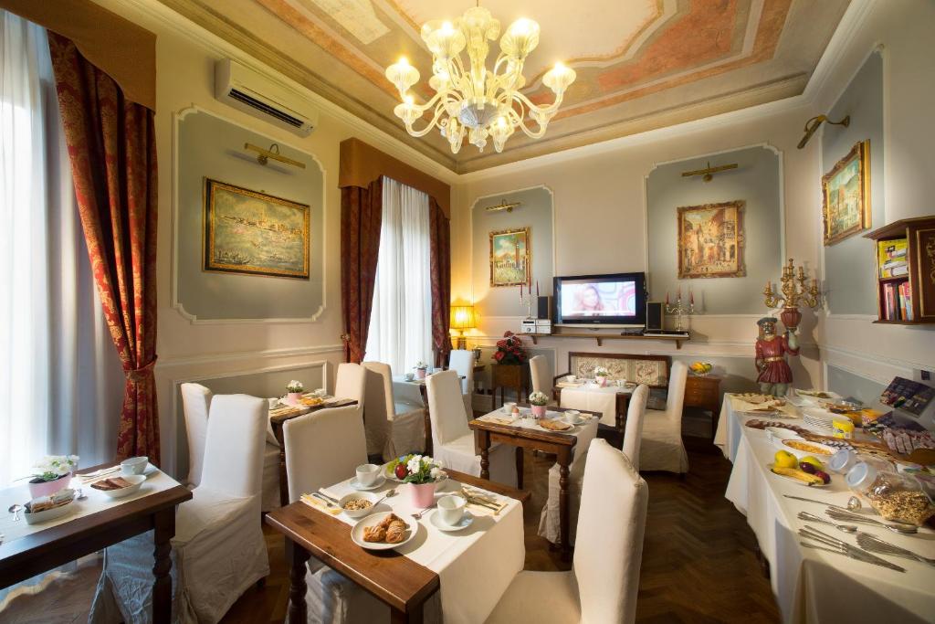 ein Restaurant mit weißen Tischen und Stühlen sowie einem Kronleuchter in der Unterkunft Il Marzocco Boutique B&B in Florenz
