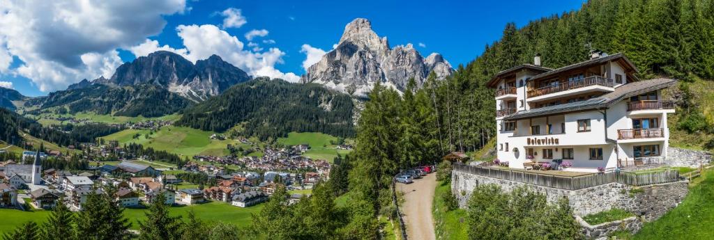 a building on a hill with mountains in the background at Residence Belavista in Corvara in Badia