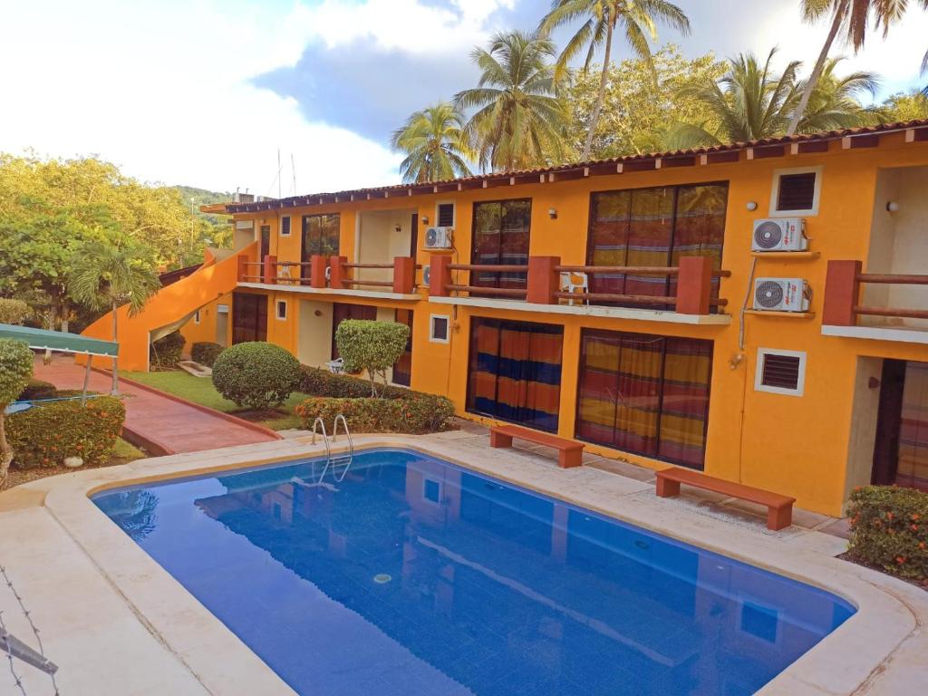 a house with a swimming pool in front of a building at Hotel J.B. in Zihuatanejo