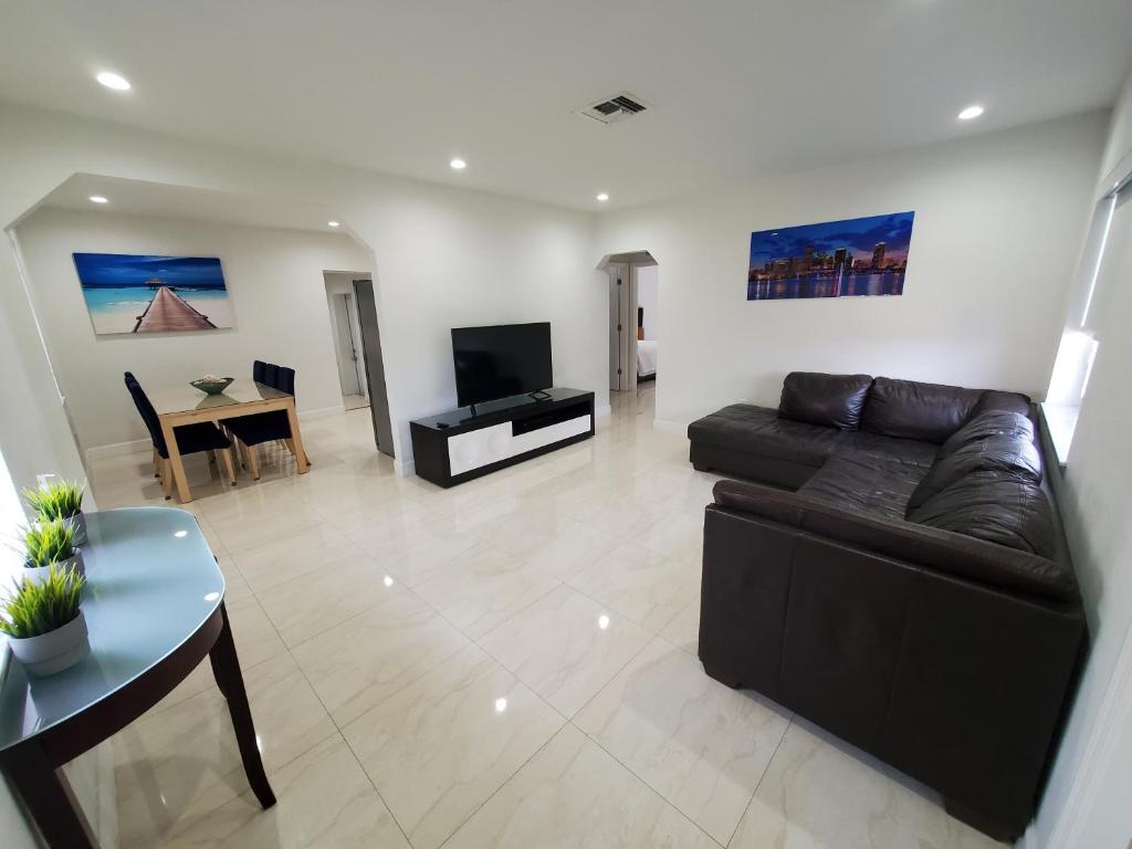 uma sala de estar com um sofá preto e uma mesa em Miami-Airport Oasis VIP House em Miami