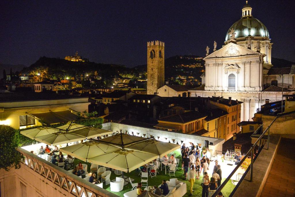 un grupo de personas de pie en la parte superior de un edificio por la noche en Hotel Vittoria, en Brescia