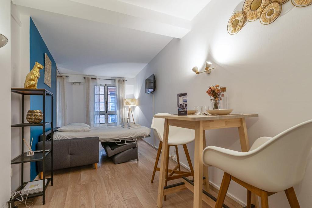 uma sala de estar com uma mesa e uma cama em Modern flat 50m from the Capitole - Toulouse - Welkeys em Toulouse