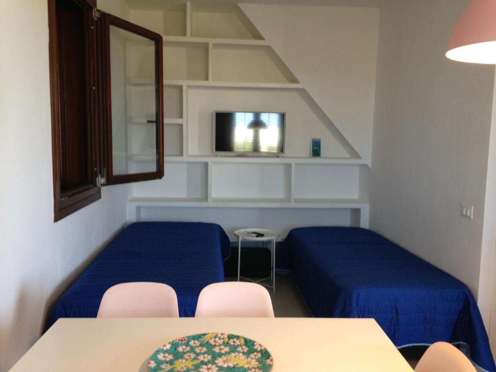 a room with two beds and a table and chairs at Le Casette a Favignana in Favignana