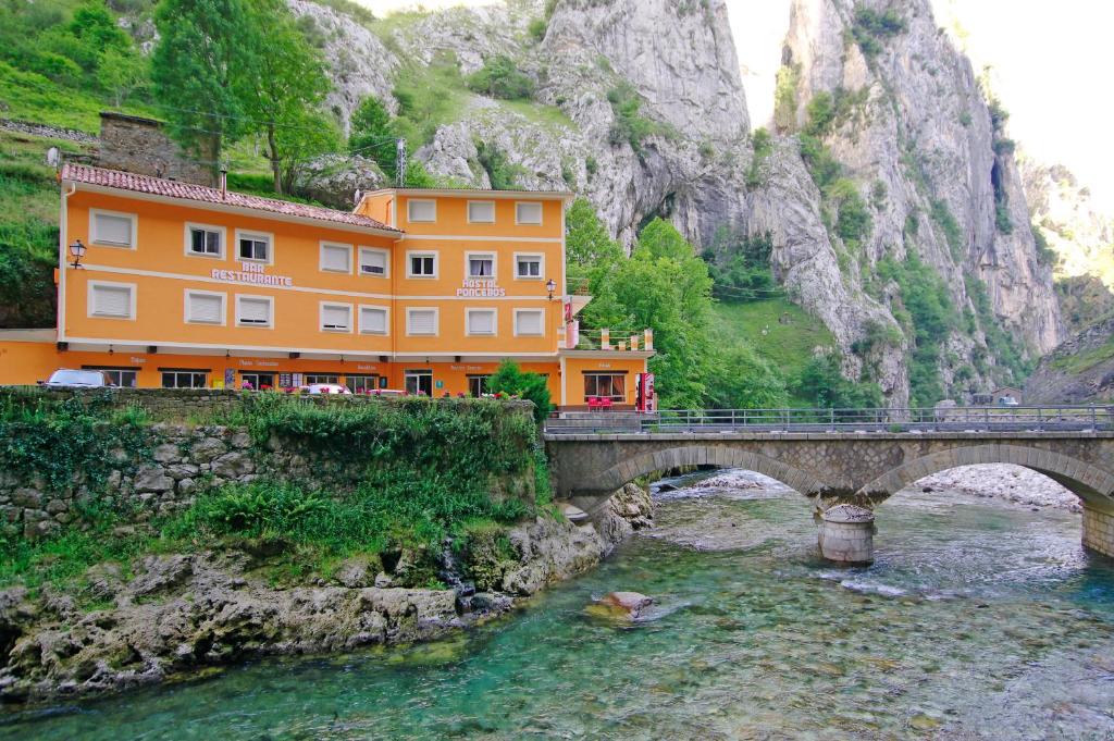 a bridge over a river in front of a building at Hostal Poncebos in Poncebos