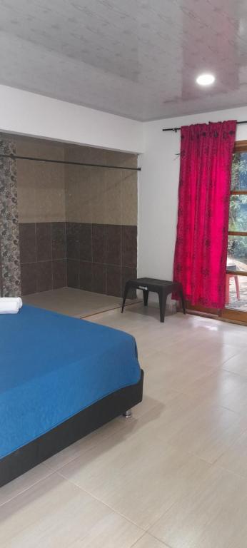 サンタ・マルタにあるEcoHostal Tierra Prometidaのベッドルーム(青いベッド1台、赤いカーテン付)