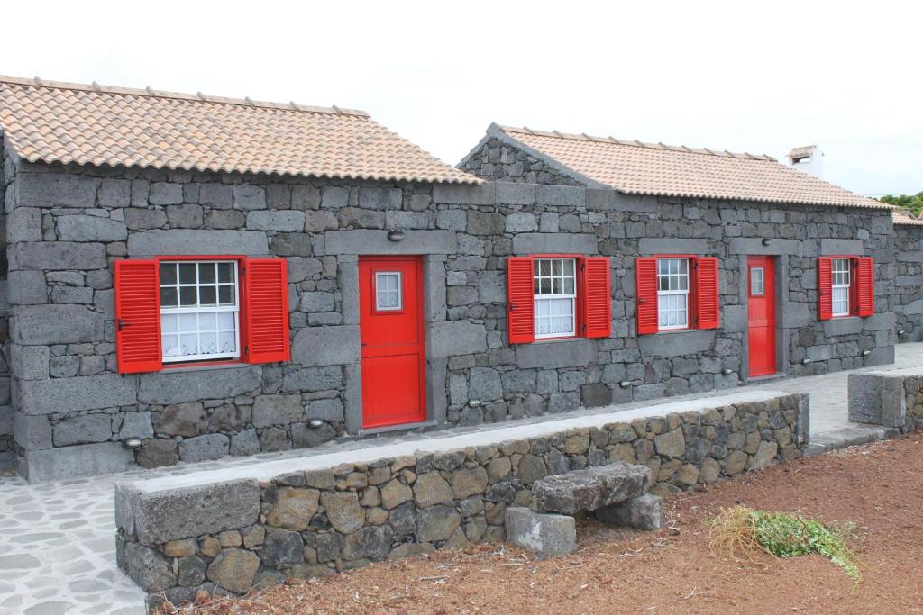 un edificio con ventanas rojas y pared de piedra en Adega Do Mirante, en São Roque do Pico