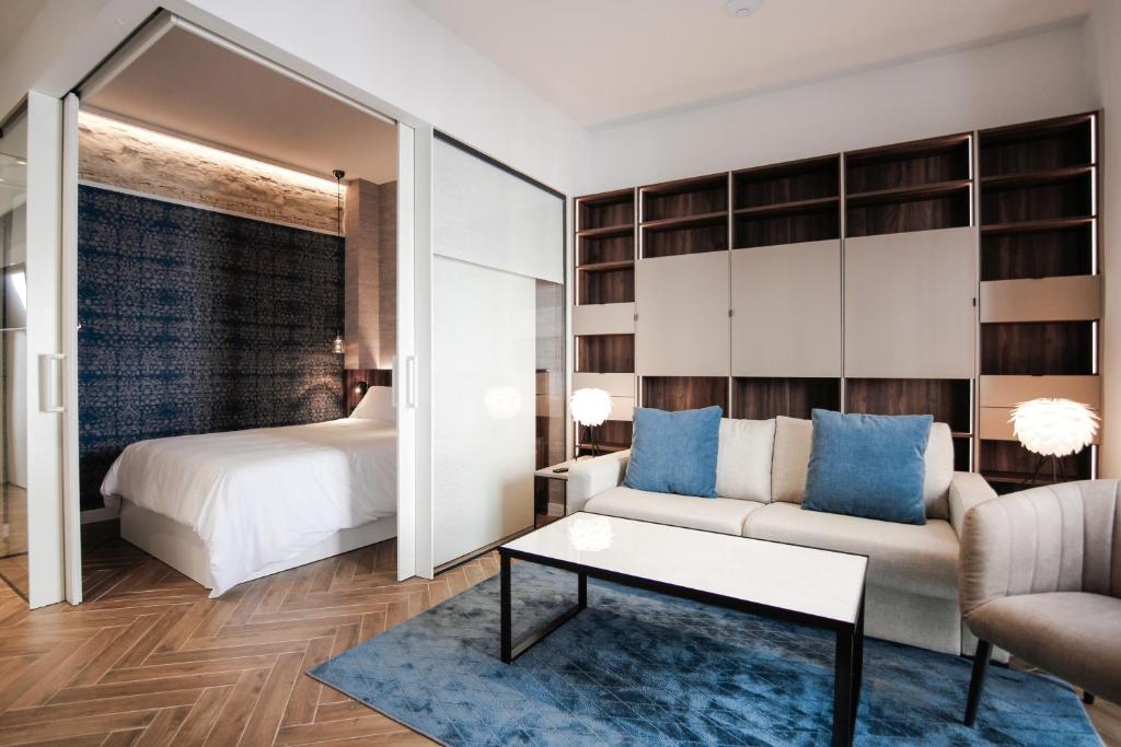 a bedroom with a bed and a couch and a table at Cabo Noval Premium Suites, by Homing U in Seville