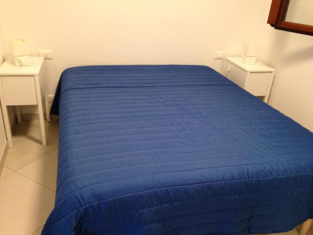 a blue bed in a room with two tables at Le Casette a Favignana in Favignana